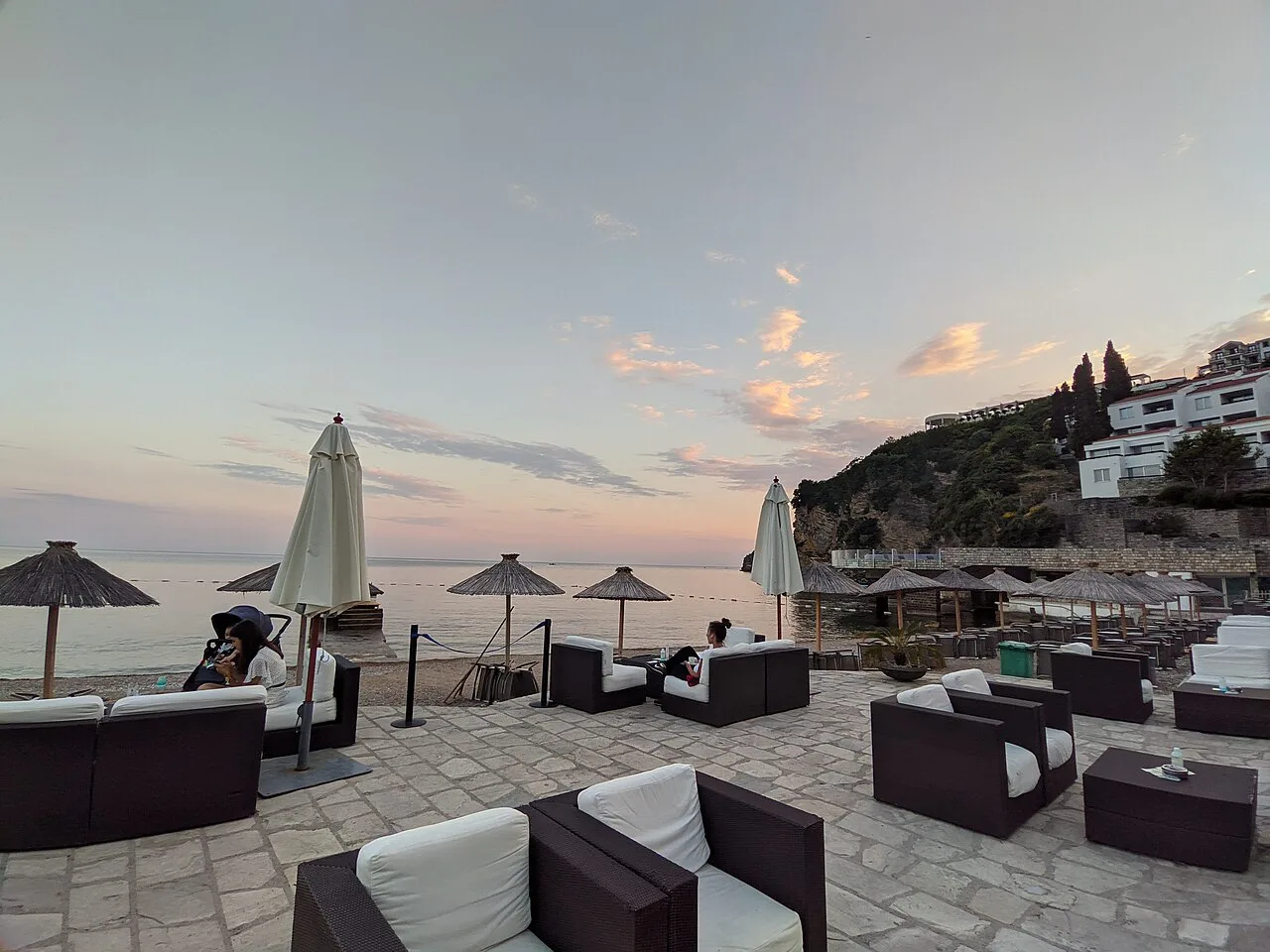 Seafront terrace seating on the Budva coast at sunset.