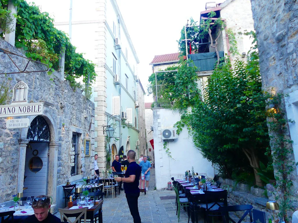 A narrow lane with café tables in Budva Old Town.