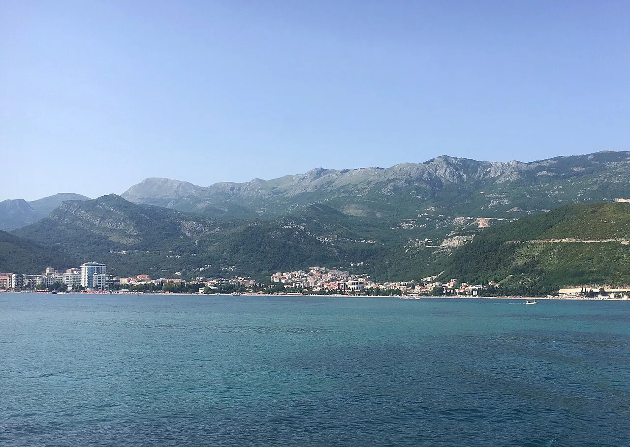 Budva seen from the sea, with mountains rising behind the town.