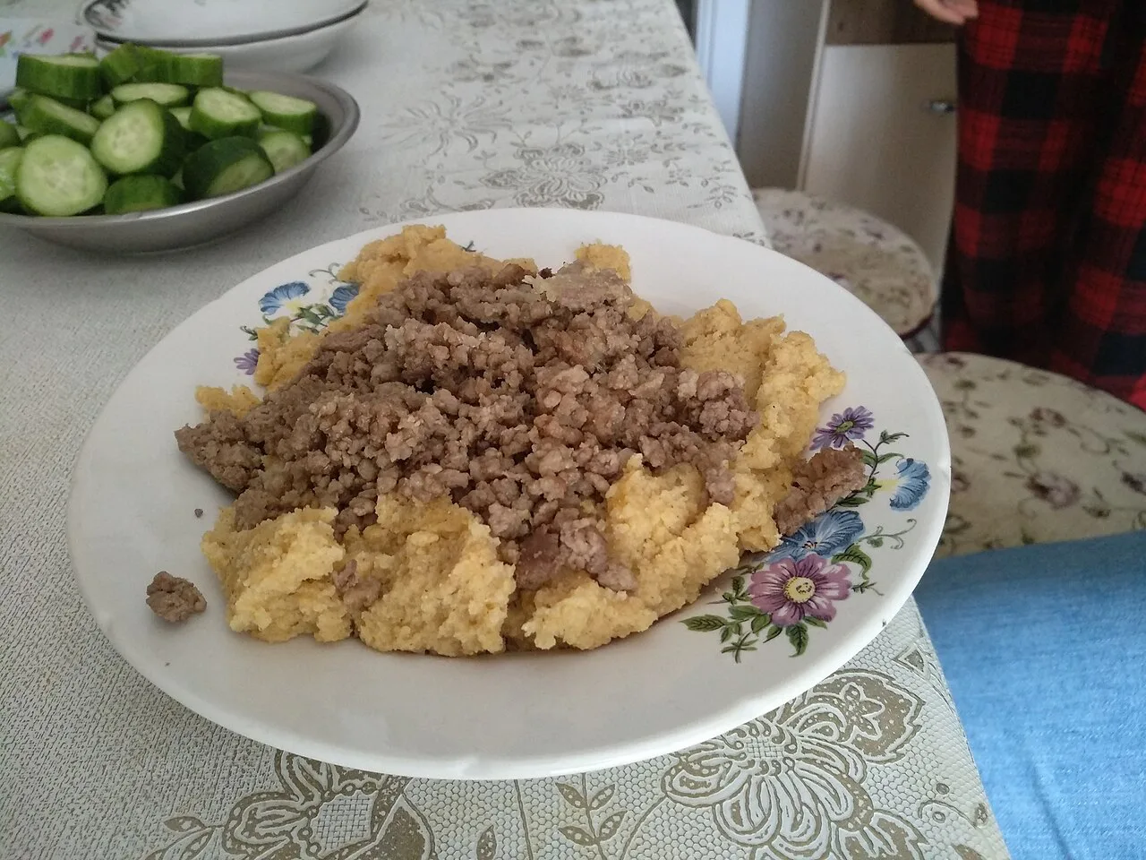 A plate of kačamak served with a side of cucumber.