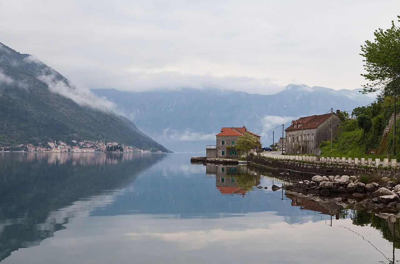 Still water reflecting the shoreline at Kostanjica on the Bay of Kotor.