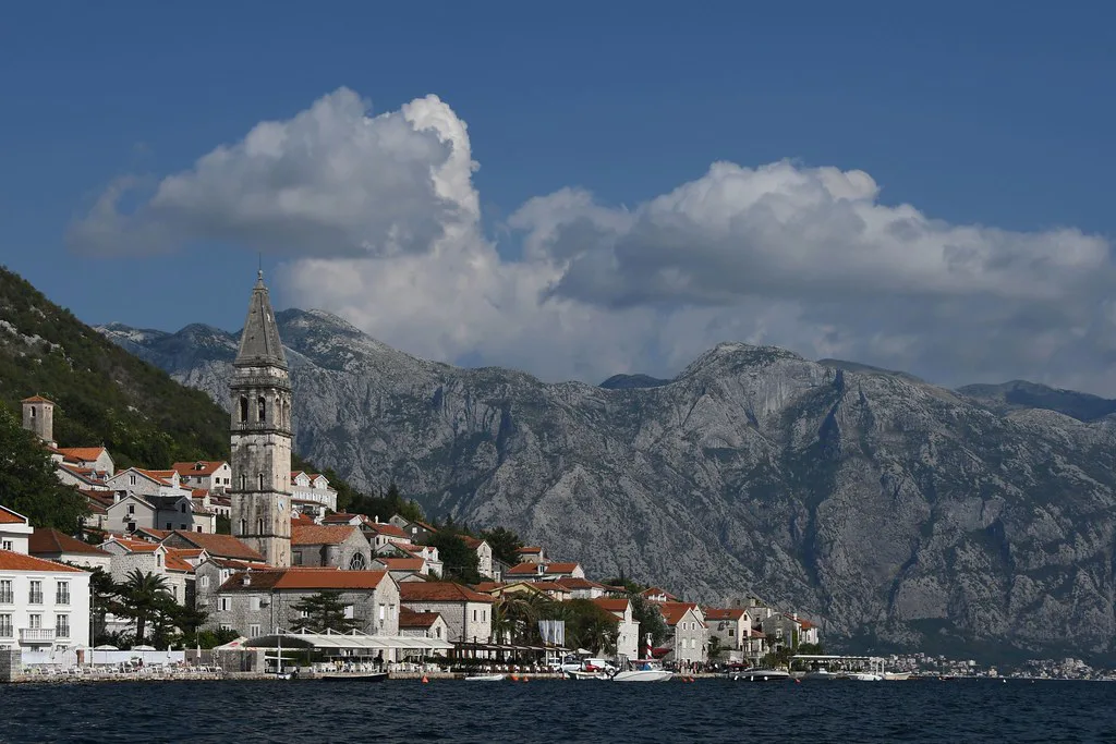 Perast's waterfront and bell tower beneath the mountains of the Bay of Kotor.