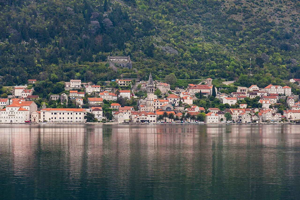 Perast seen across the Bay of Kotor, with its houses lining the shore.