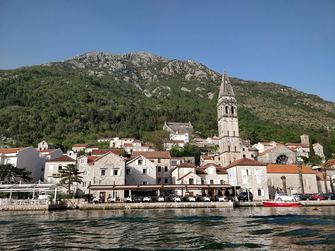 Perast and its bell tower seen from a boat.