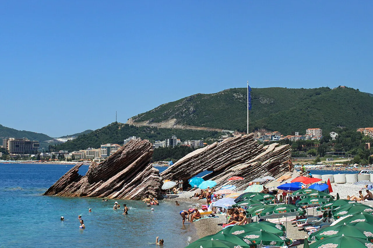 Striated rocks and sunshades on the beach at Rafailovići.