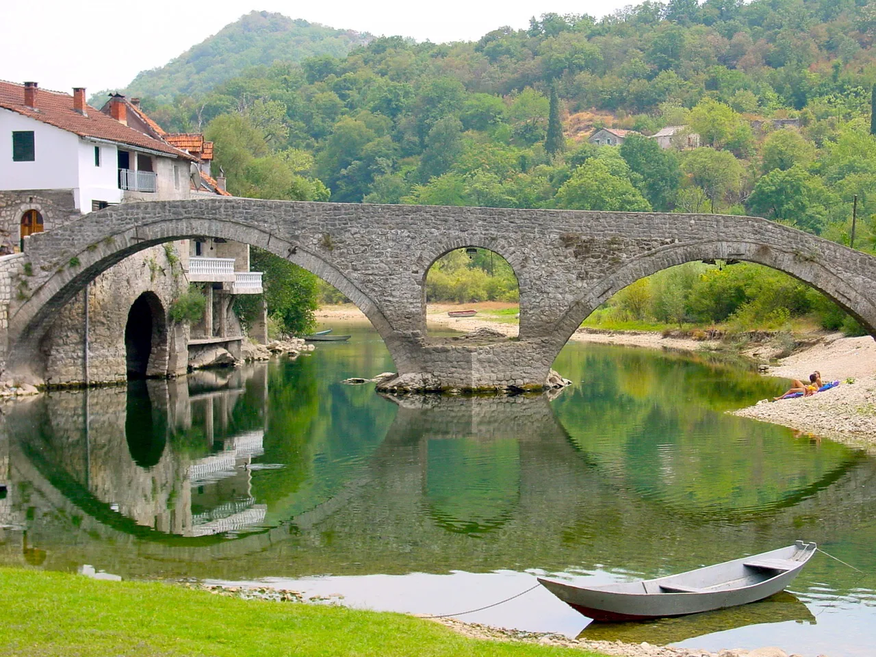 The arched stone bridge at Rijeka Crnojevića reflected in the river.