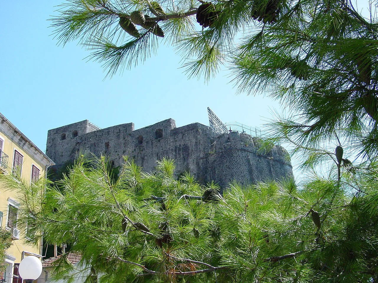Fortified city walls of Herceg Novi seen through pine trees.