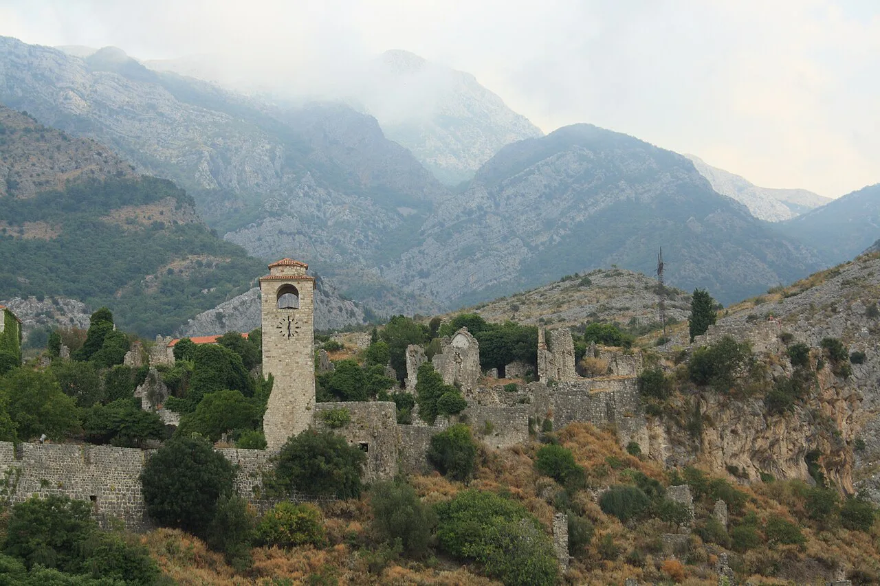The ruined old town of Stari Bar with its clock tower beneath the mountains.