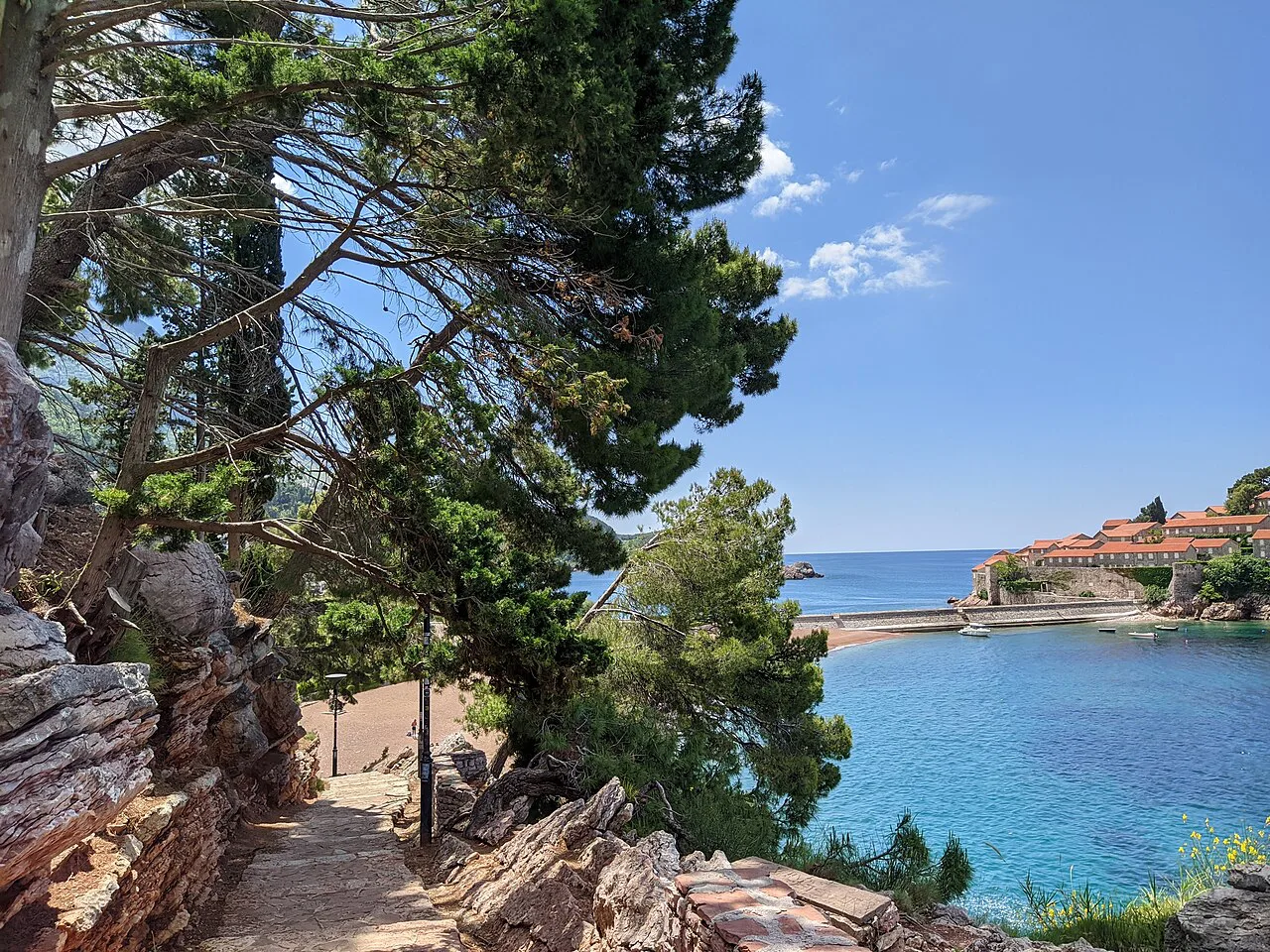 Sveti Stefan island seen through pines from the coastal path.