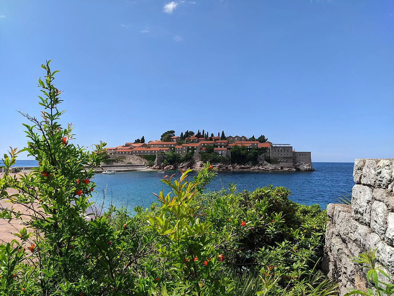 Sveti Stefan island seen over coastal greenery.