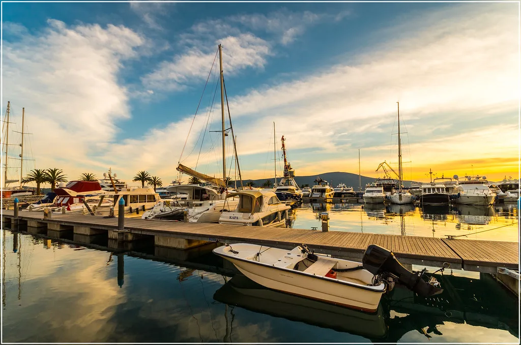 Yachts moored in a Tivat marina at sunset.
