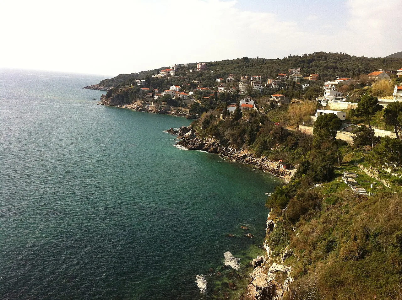Ulcinj's coastline with houses on the hillside above the sea.