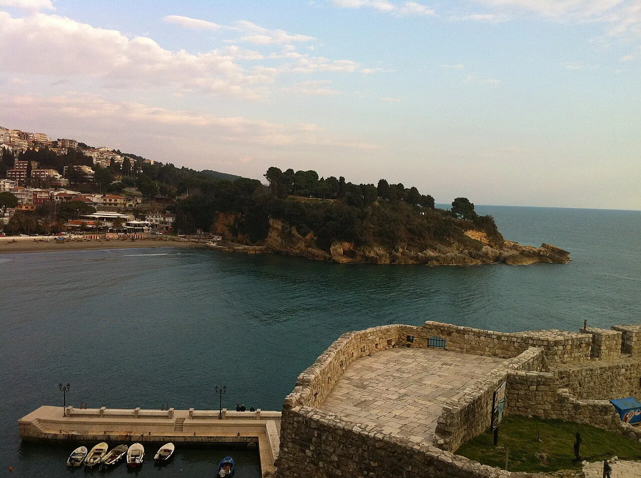 Ulcinj Old Town walls above the sea, with the wooded coastline beyond.